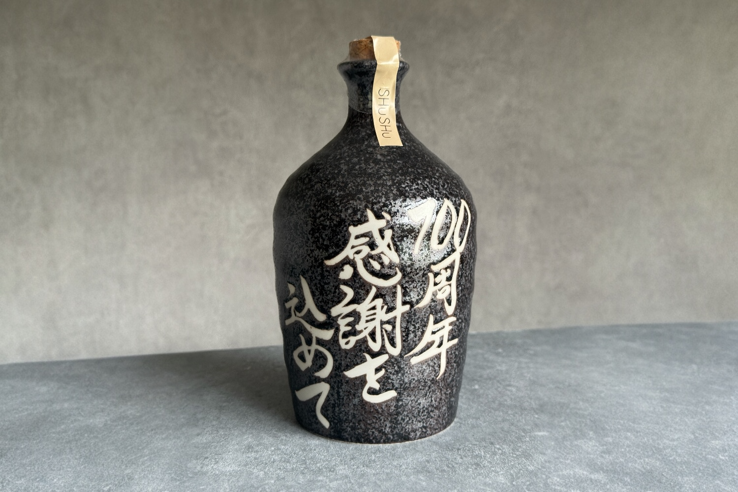 高級感のある美濃焼・黒窯変のボトルに手書きされた創立100周年記念の贈答品