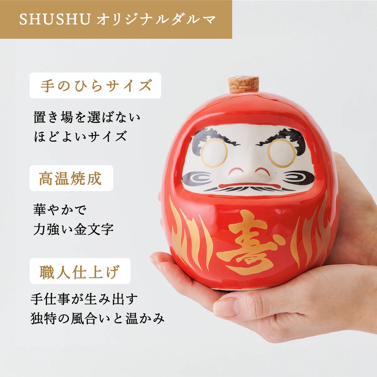 名入れ酒器ギフトSHUSHU。手のひらサイズの赤いダルマ型陶器ボトルに『喜』の金文字。高温焼成と職人仕上げによる華やかで温かみのある逸品