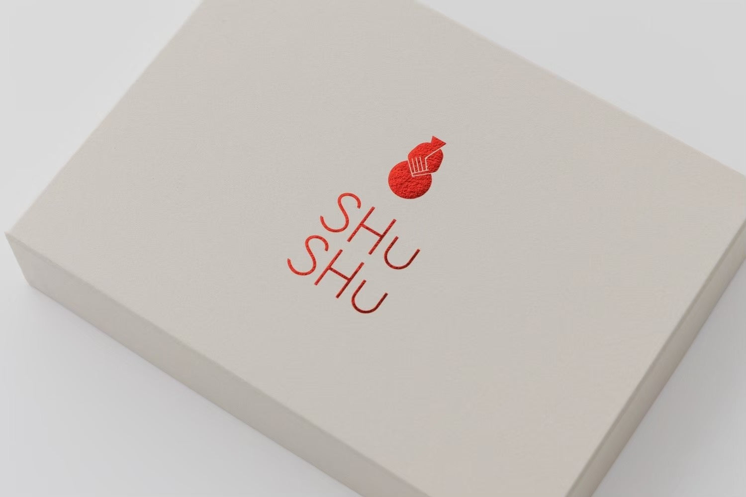 美濃焼名入れギフトブランンドSHUSHUの白いギフトボックス。中央に赤い徳利マークとSHUSHUロゴが印刷され、上品清潔感のあるパッケージデザイン。